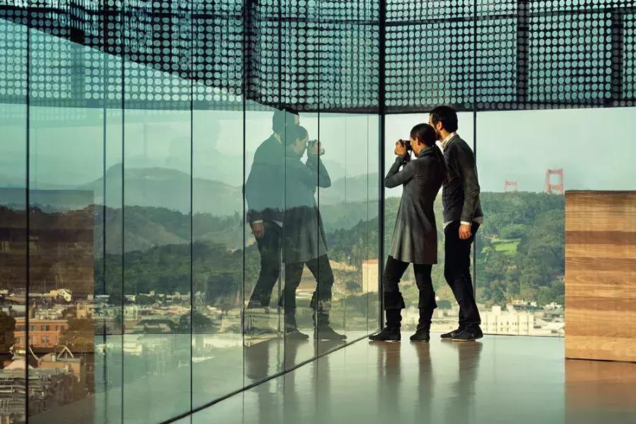 Two people peer through glass walls at the de Young Museum in 贝博体彩app.